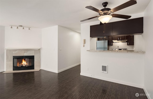 unfurnished living room with ceiling fan, dark hardwood / wood-style floors, and a tiled fireplace