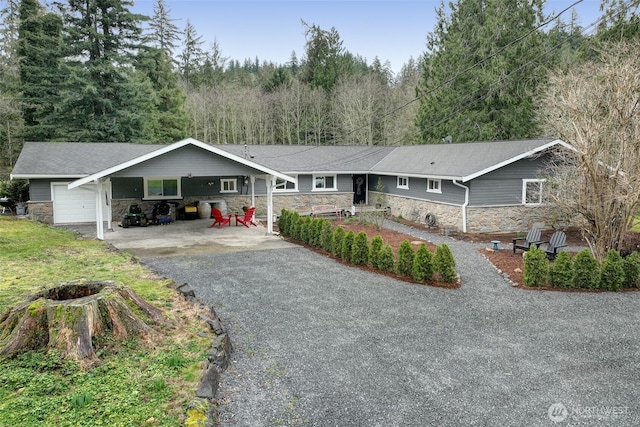 ranch-style house featuring stone siding, aphalt driveway, and an attached carport