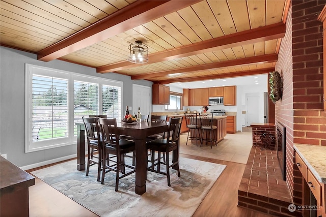 dining area featuring sink, light hardwood / wood-style flooring, wooden ceiling, beamed ceiling, and a fireplace