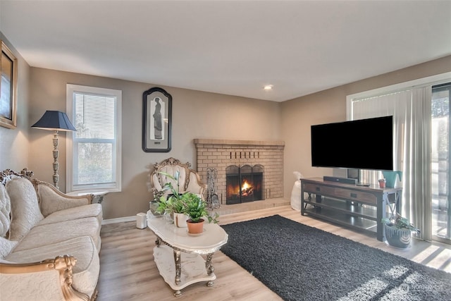 living room featuring a brick fireplace, hardwood / wood-style flooring, and a healthy amount of sunlight