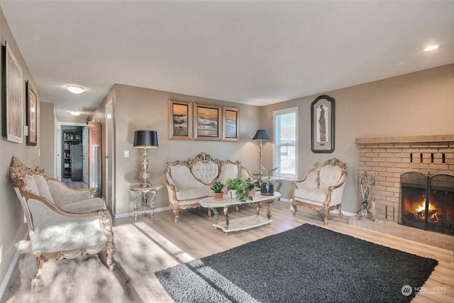 living room featuring a brick fireplace and wood-type flooring