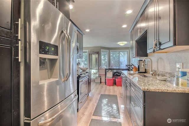 kitchen featuring stainless steel appliances, light stone countertops, sink, and light hardwood / wood-style flooring