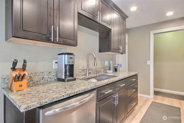 kitchen featuring sink, dark brown cabinetry, light stone countertops, stainless steel dishwasher, and light wood-type flooring