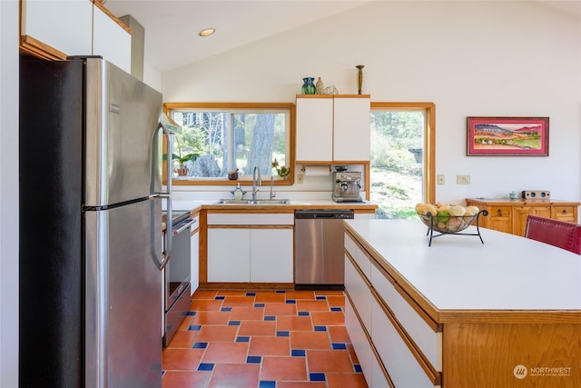 kitchen featuring sink, stainless steel appliances, a wealth of natural light, white cabinets, and vaulted ceiling