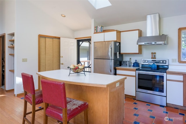 kitchen featuring white cabinetry, stainless steel appliances, a center island, and wall chimney range hood