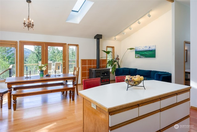 kitchen featuring a kitchen island, decorative light fixtures, a wood stove, white cabinets, and light hardwood / wood-style floors
