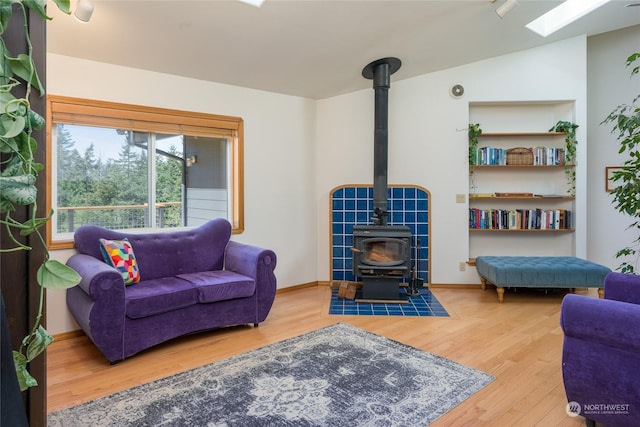living room with lofted ceiling with skylight, hardwood / wood-style floors, and a wood stove