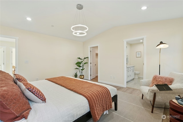 bedroom featuring vaulted ceiling, ensuite bathroom, a chandelier, a spacious closet, and light hardwood / wood-style floors