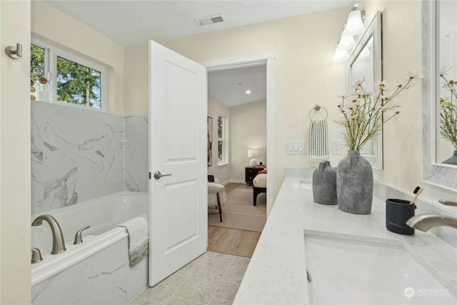 bathroom with a relaxing tiled tub and vanity