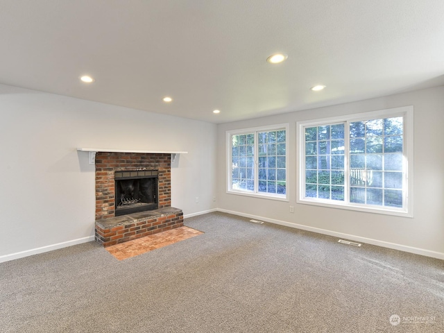 unfurnished living room with carpet flooring and a brick fireplace