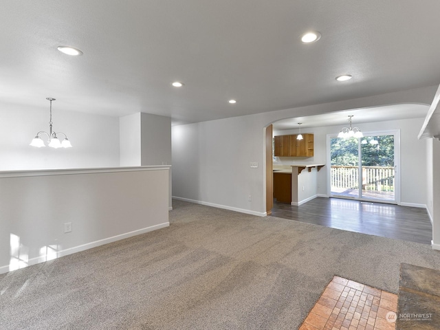 unfurnished living room with a chandelier and dark colored carpet