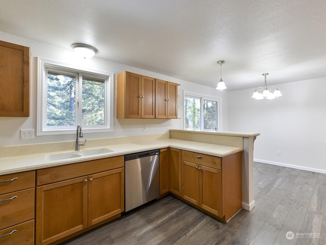 kitchen featuring pendant lighting, sink, dark hardwood / wood-style flooring, stainless steel dishwasher, and kitchen peninsula