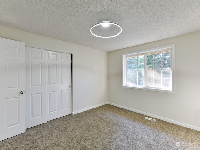 unfurnished bedroom featuring carpet, a textured ceiling, and a closet