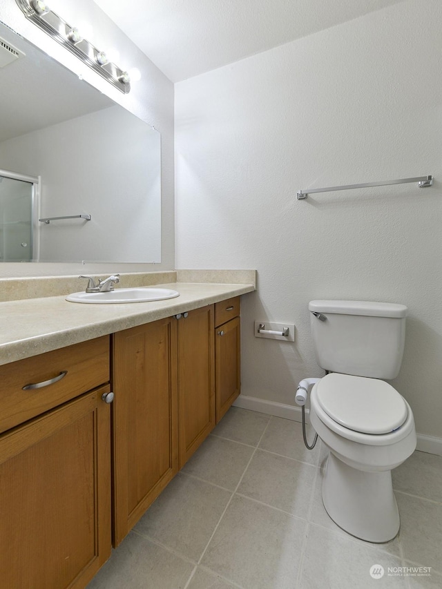 bathroom with tile patterned flooring, vanity, a shower with shower door, and toilet