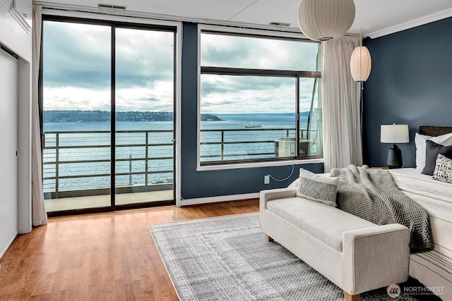 bedroom featuring a water view, crown molding, and wood finished floors