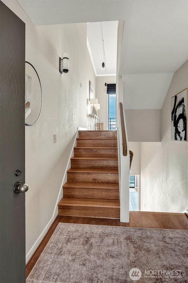 stairs featuring lofted ceiling, baseboards, and wood finished floors