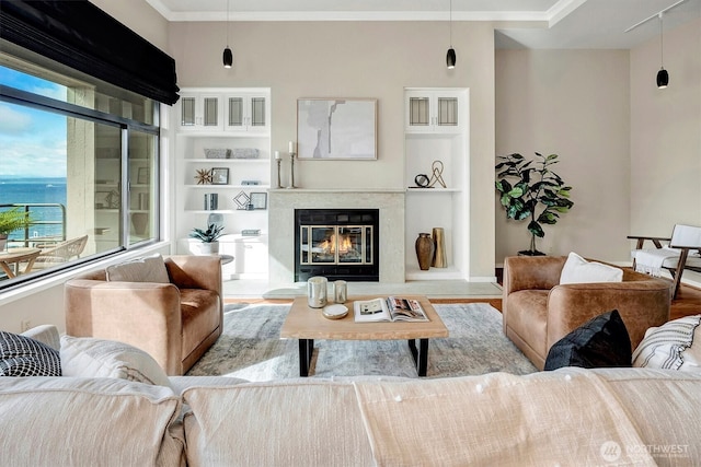 living area featuring ornamental molding, a fireplace, wood finished floors, and built in shelves