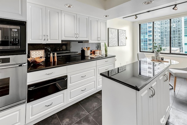 kitchen with oven, black electric cooktop, backsplash, a warming drawer, and dark countertops