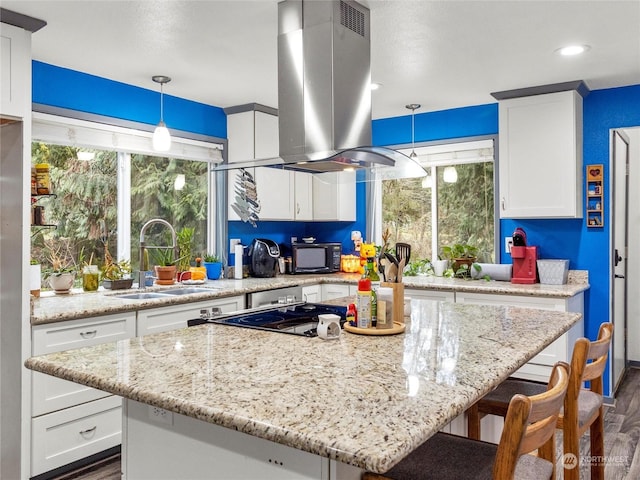 kitchen with sink, decorative light fixtures, white cabinets, and island exhaust hood