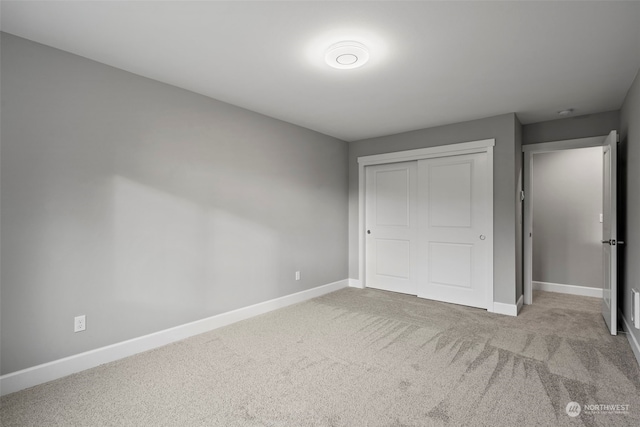 unfurnished bedroom with light colored carpet and a closet