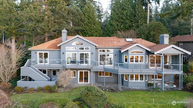 back of property with a wooden deck and a lawn