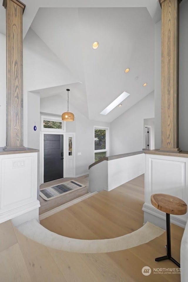 foyer featuring light hardwood / wood-style flooring, high vaulted ceiling, and a skylight