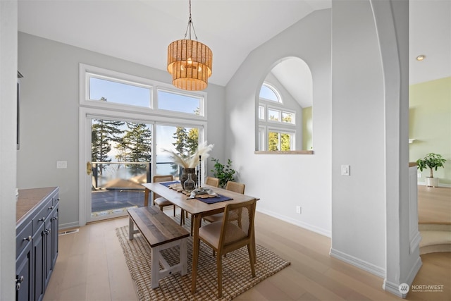 dining space featuring lofted ceiling, a notable chandelier, and light wood-type flooring