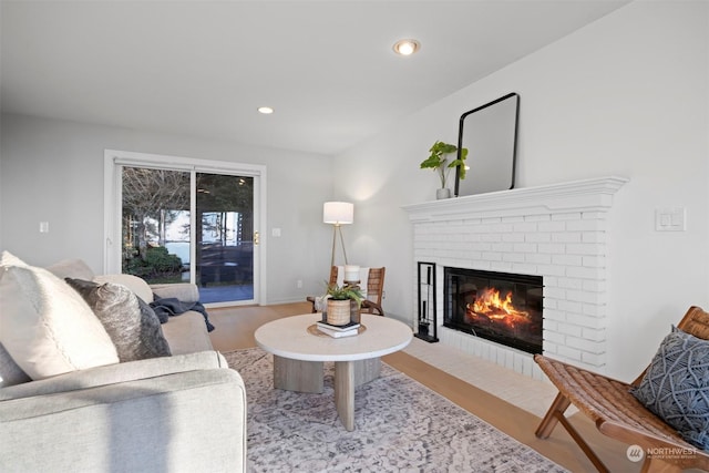 living room with a brick fireplace and light hardwood / wood-style floors