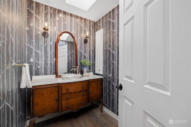 bathroom with vanity, a skylight, and wood-type flooring