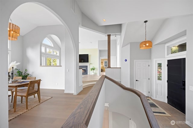 hallway featuring high vaulted ceiling and light hardwood / wood-style flooring