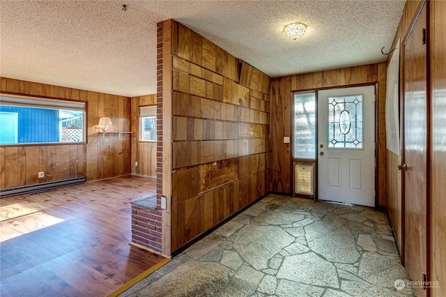 entryway featuring a baseboard heating unit, wood-type flooring, wooden walls, and a textured ceiling