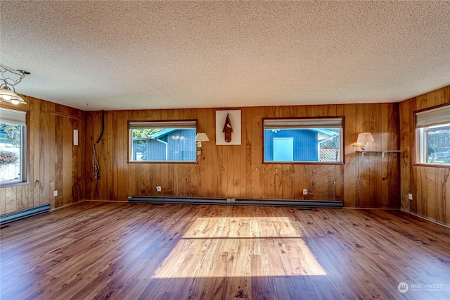 unfurnished room featuring hardwood / wood-style flooring, a baseboard radiator, and a textured ceiling