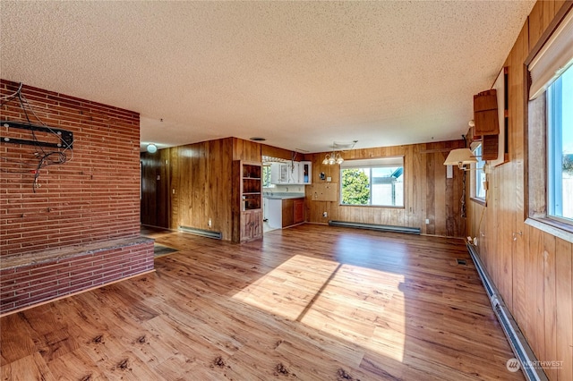 unfurnished living room with hardwood / wood-style floors, baseboard heating, and wood walls