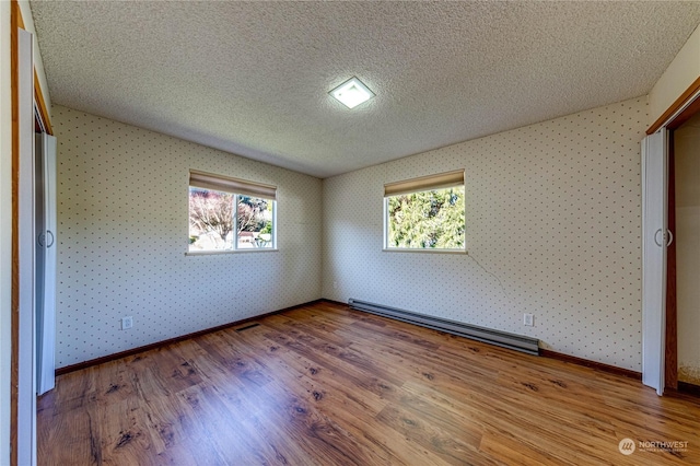 unfurnished bedroom featuring a baseboard heating unit, light hardwood / wood-style flooring, and a textured ceiling