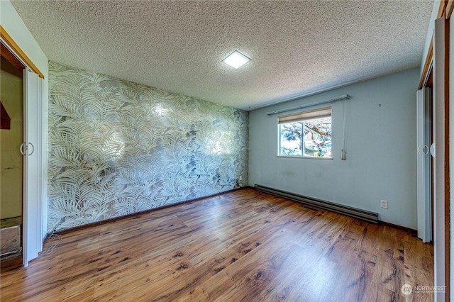 unfurnished room with a baseboard heating unit, hardwood / wood-style floors, and a textured ceiling