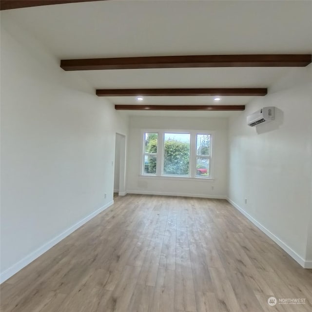 unfurnished room with light wood-type flooring, a wall mounted AC, and beam ceiling