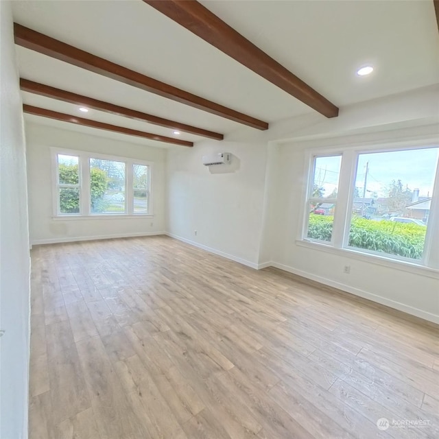 spare room with beam ceiling, light hardwood / wood-style flooring, and a wall unit AC