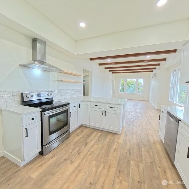 kitchen featuring white cabinetry, wall chimney range hood, light hardwood / wood-style floors, and appliances with stainless steel finishes