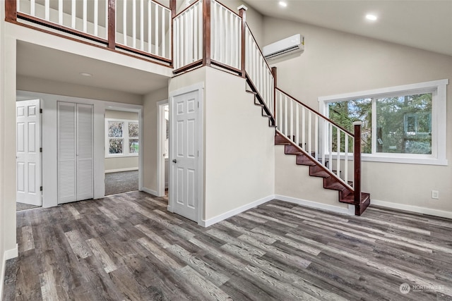 entrance foyer featuring dark wood-type flooring, high vaulted ceiling, and a wall mounted AC