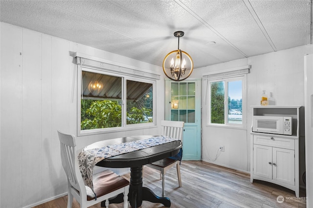 dining room with an inviting chandelier, wood-type flooring, and a textured ceiling