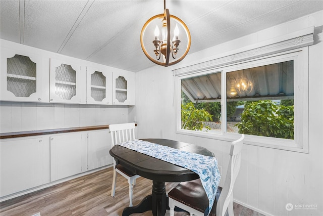 dining space featuring wood-type flooring, a textured ceiling, and an inviting chandelier