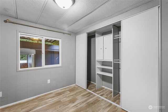 unfurnished bedroom with a textured ceiling, a closet, and light wood-type flooring