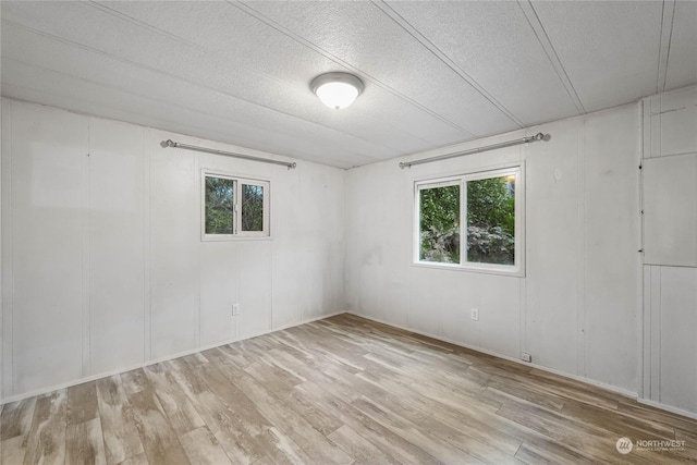 unfurnished room featuring light hardwood / wood-style flooring and a textured ceiling