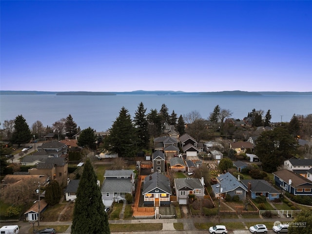 aerial view at dusk featuring a water view