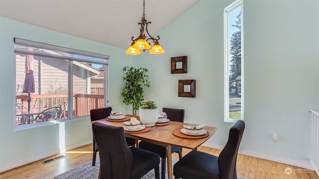 dining space with vaulted ceiling, an inviting chandelier, and light wood-type flooring