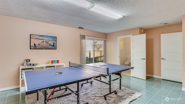 recreation room with tile patterned floors and a textured ceiling