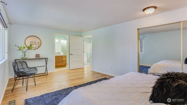 bedroom featuring connected bathroom, light hardwood / wood-style flooring, and a textured ceiling