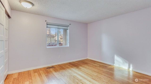 spare room featuring a textured ceiling and light wood-type flooring