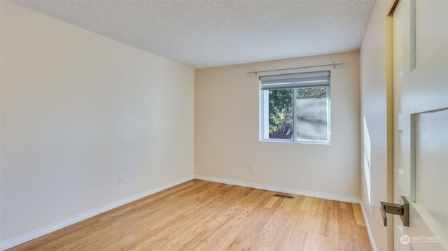 unfurnished room with hardwood / wood-style flooring and a textured ceiling