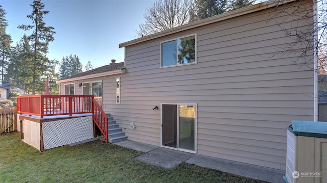 rear view of house featuring a lawn and a deck